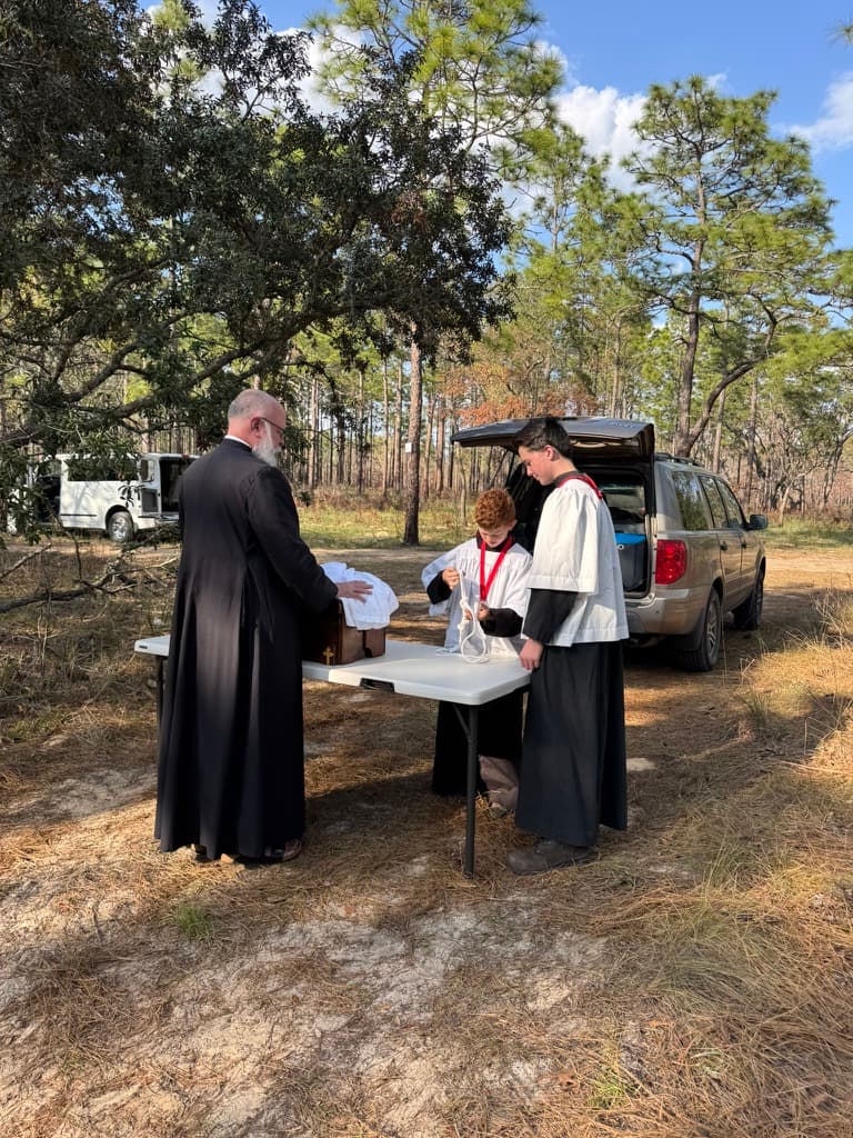 Priest and altar servers preparing for outdoor Mass at camp