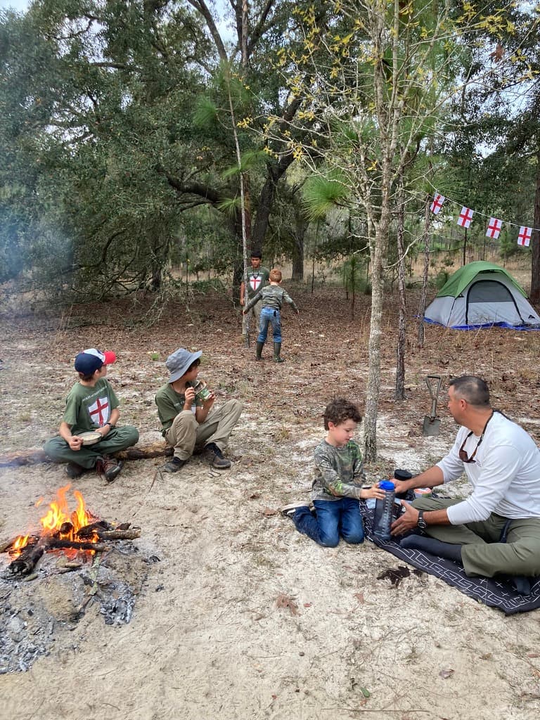 Boys and fathers around a campfire at primitive campout